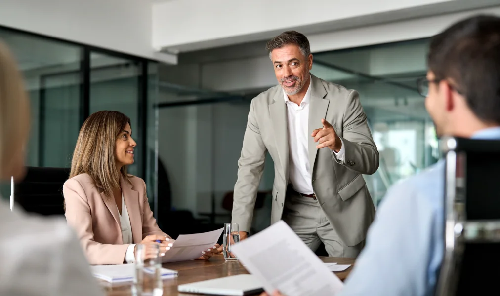 Executive board team people having discussion at conference meeting. Mature older business man manager CEO leading group corporate meeting in boardroom working together at office table.