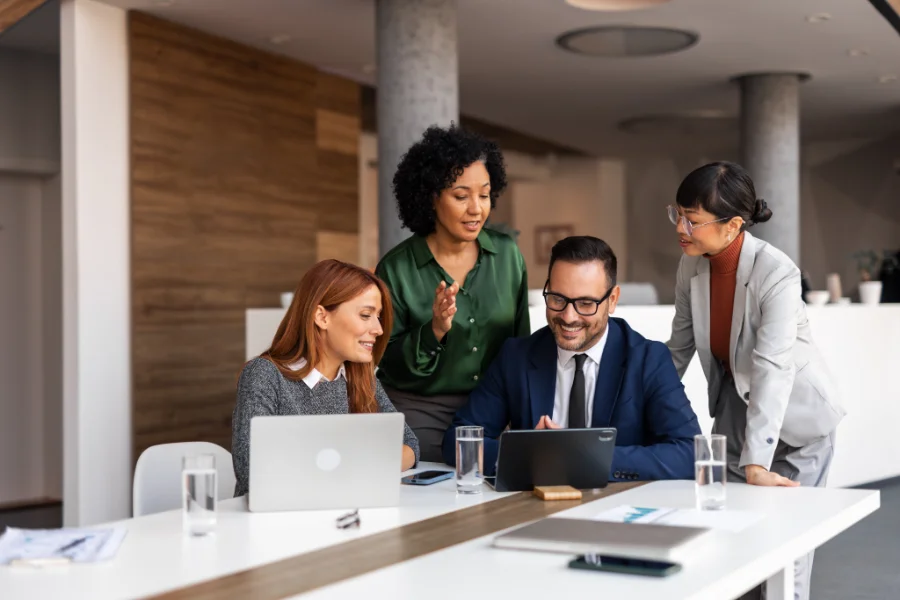 A group of colleagues working together in a contemporary office setting, engaging in teamwork and brainstorming. The team appears professional and focused, utilizing technology to discuss and share ideas.
